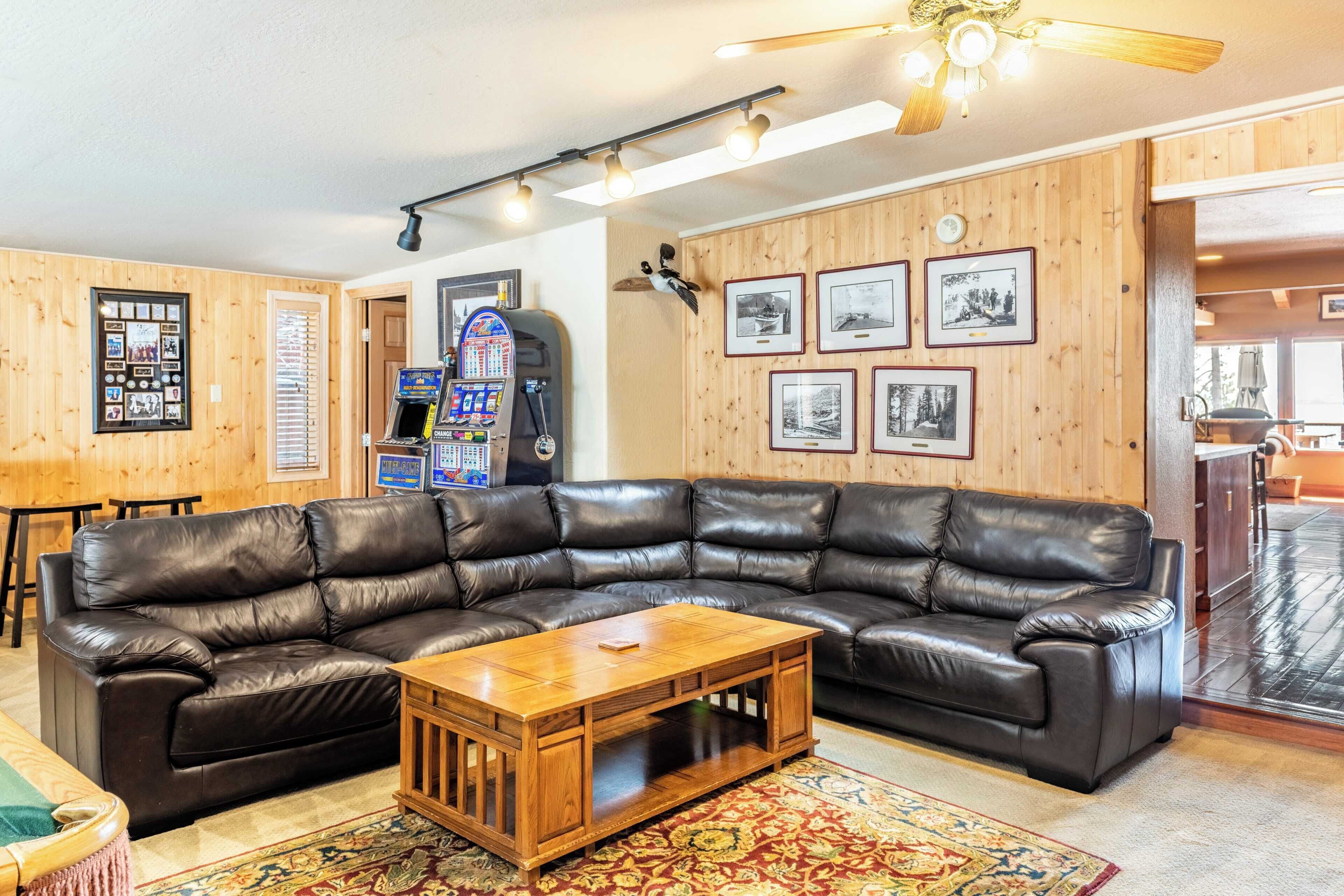 A cozy living room with a large leather sectional sofa, a wooden coffee table, and a wall adorned with framed photographs.