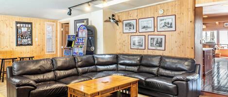 A cozy living room with a large leather sectional sofa, a wooden coffee table, and a wall adorned with framed photographs.