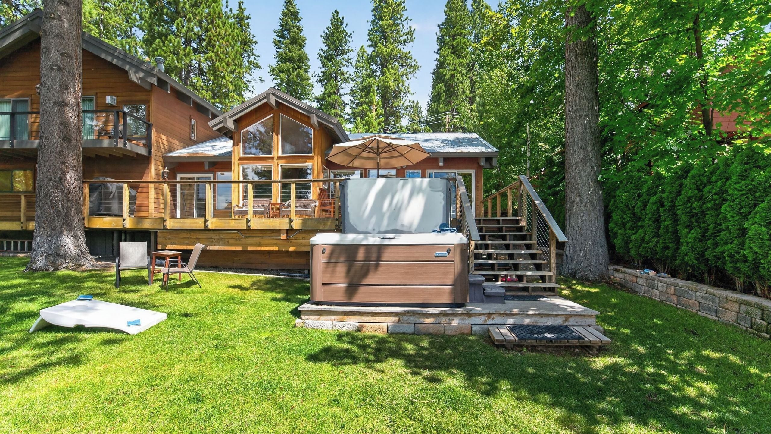 Una cabaña de madera con terraza, mobiliario exterior y un jacuzzi.