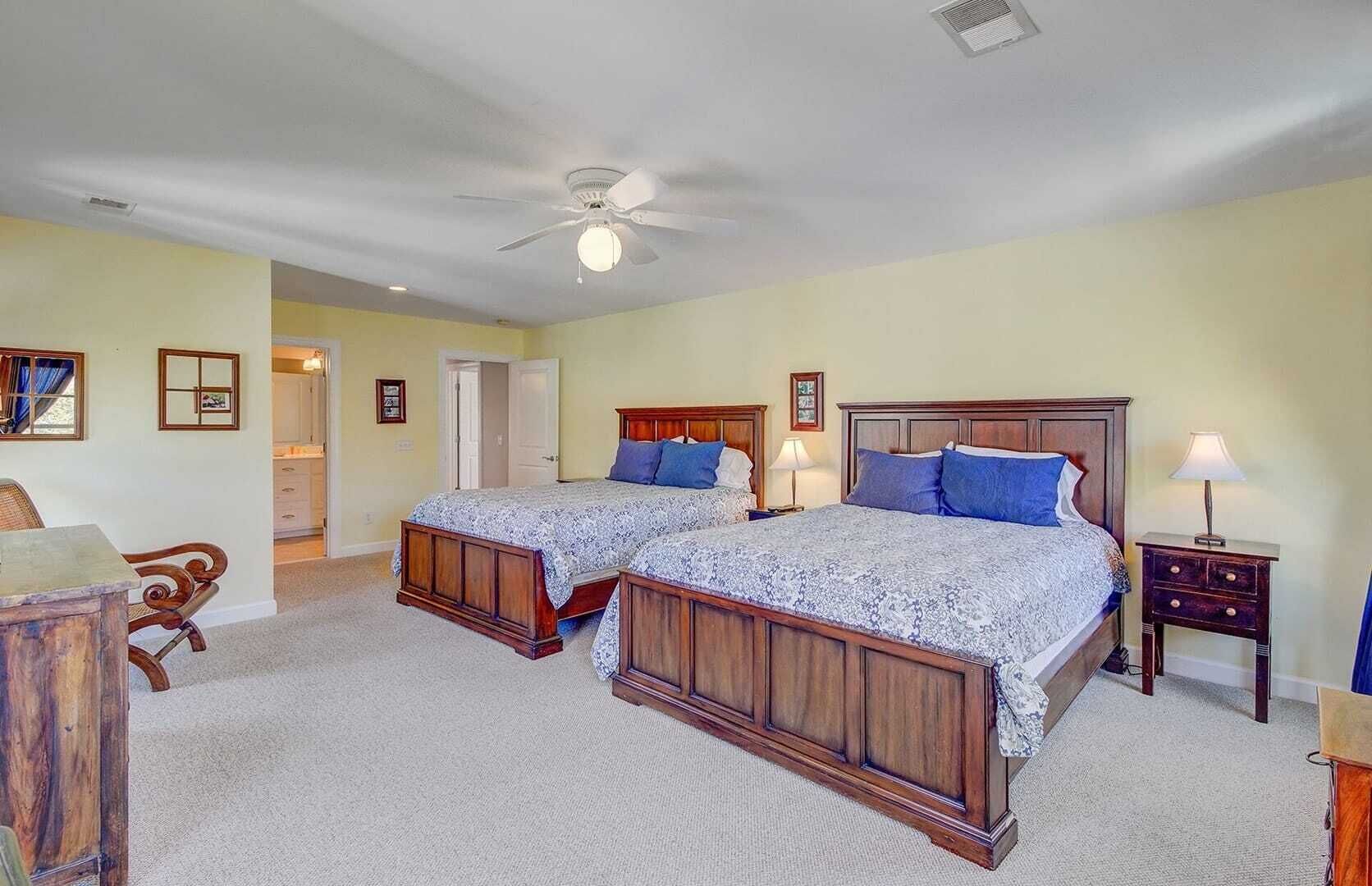 A bedroom with two wooden beds, a ceiling fan, and a nightstand with a lamp.