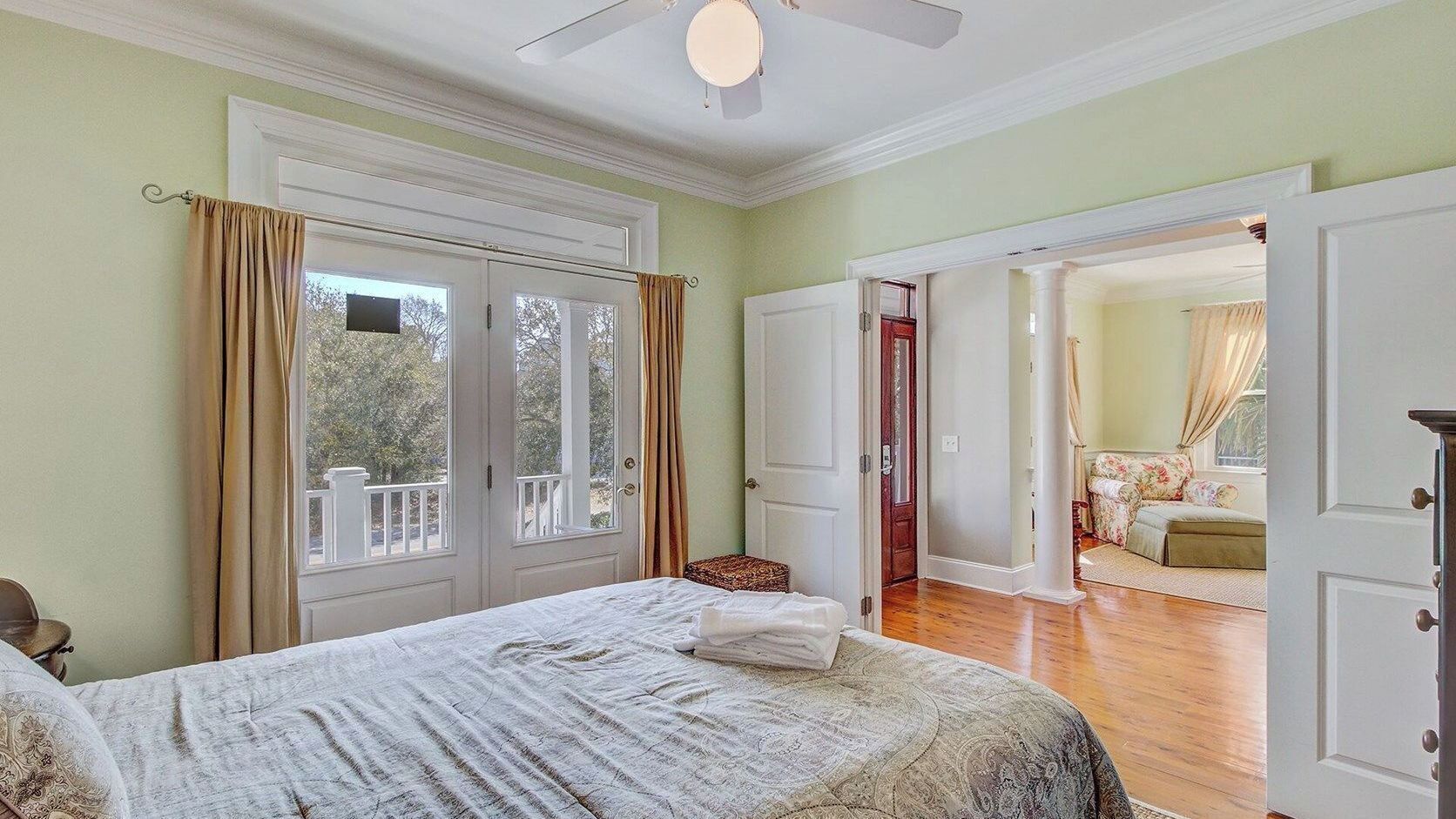 Ein Schlafzimmer mit Bett, Fenster, einer Tür zu einem Balkon und Blick ins Freie.