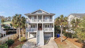 A two-story house with a front porch, a garage, and a staircase leading to the entrance. - 7 41st Avenue by Avantstay Private Pool, Near Beach (Isle of Palms)