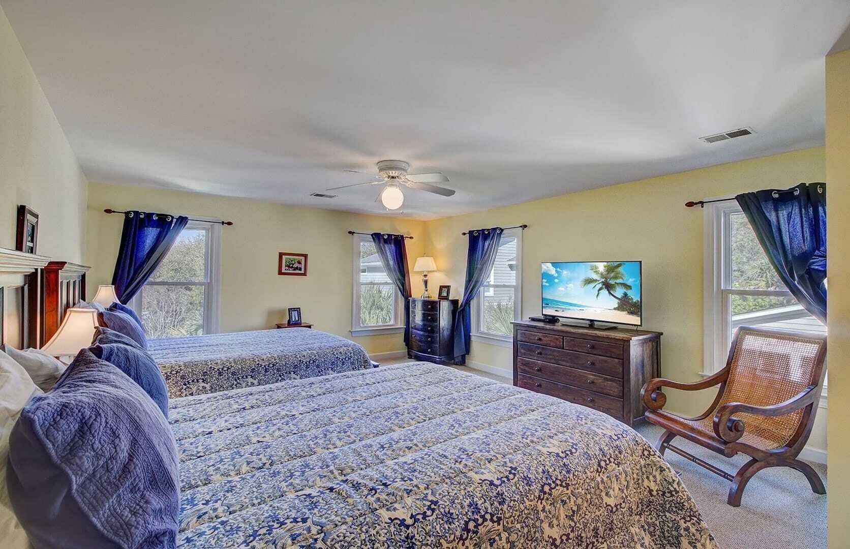 A bedroom with two beds, a TV, a dresser, and a chair.