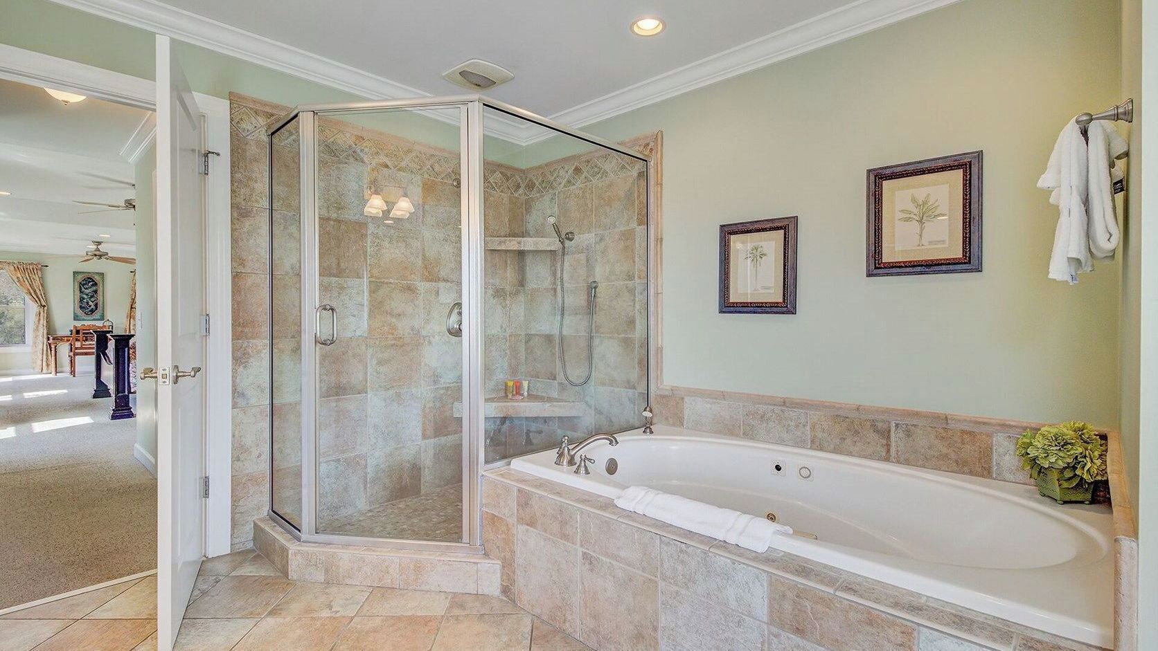 A bathroom with a glass-enclosed shower, a freestanding bathtub, and two framed pictures on the wall.