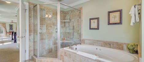 A bathroom with a glass-enclosed shower, a freestanding bathtub, and two framed pictures on the wall.