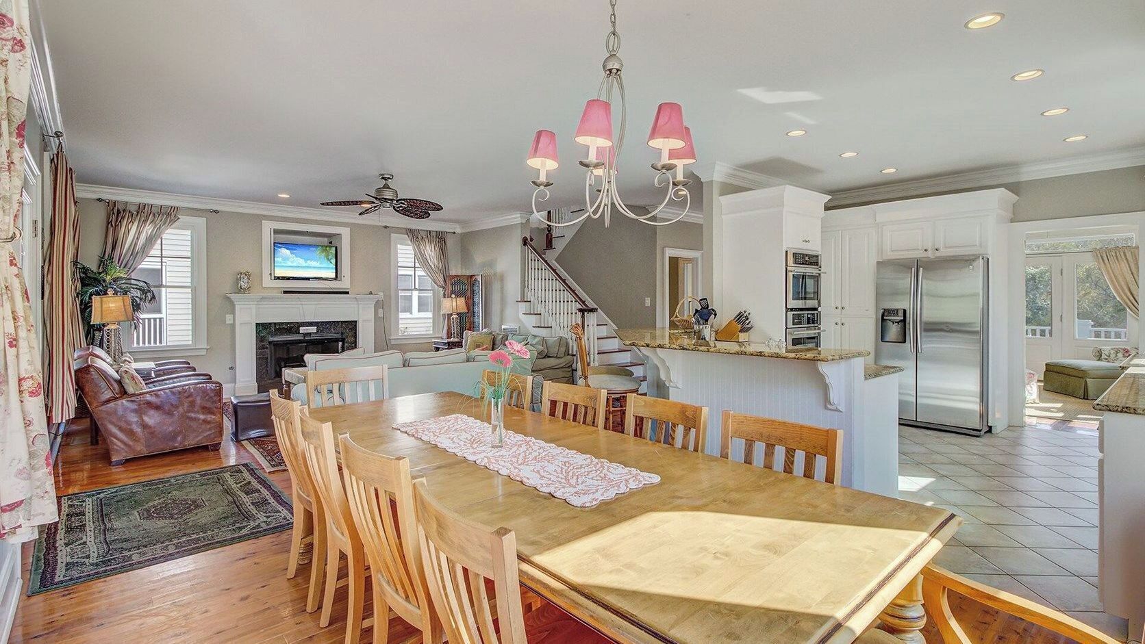 A spacious kitchen with a dining area, wooden furniture, and a chandelier.