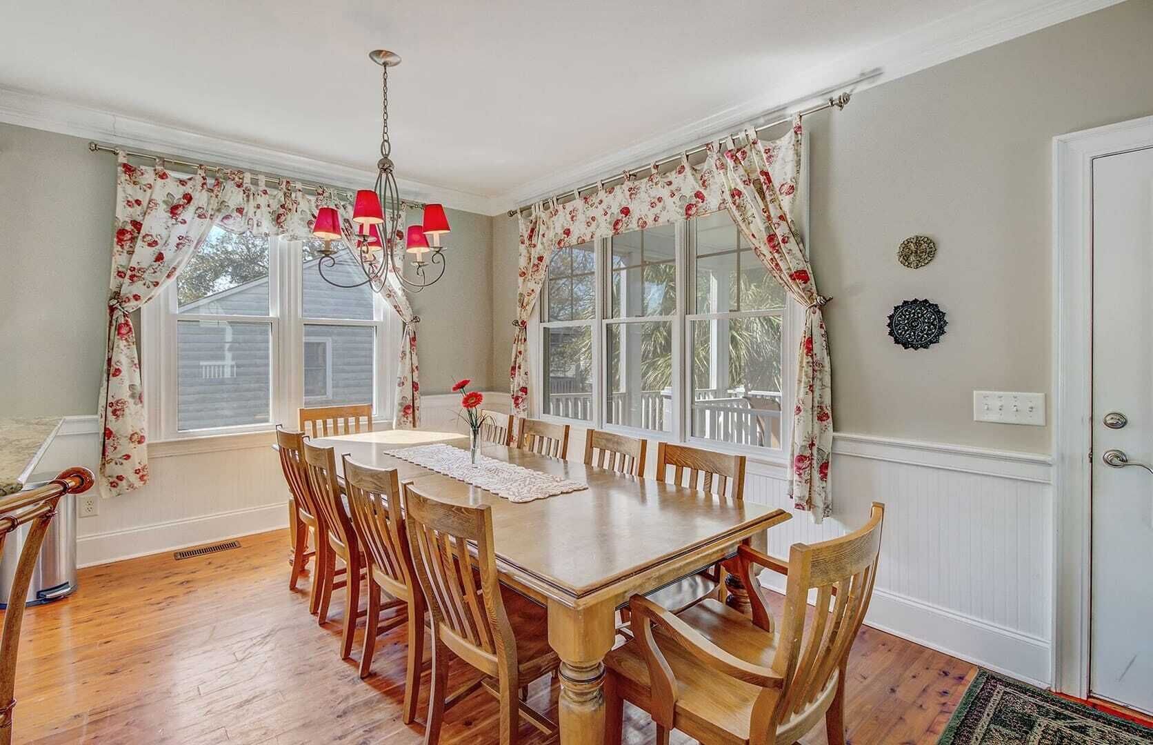 Ein Esszimmer mit Holztisch und -stühlen, blumigen Vorhängen und einer Chandelier.