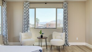 A room with two chairs, a small table, and a bed. - Sleeps 16! Pool Oasis w/ Game Room, Hot Tub, Fire Pit Desert Eden by Avantstay (Coachella)