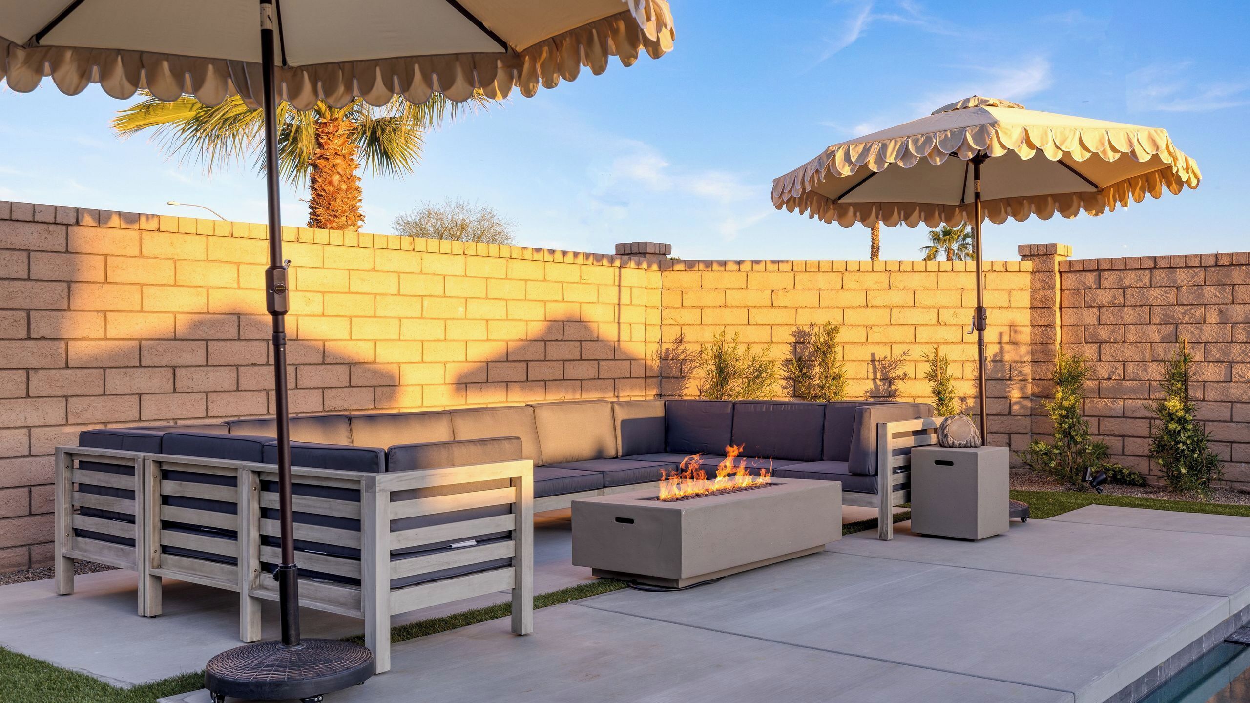 A patio with a fire pit, outdoor seating, and umbrellas.