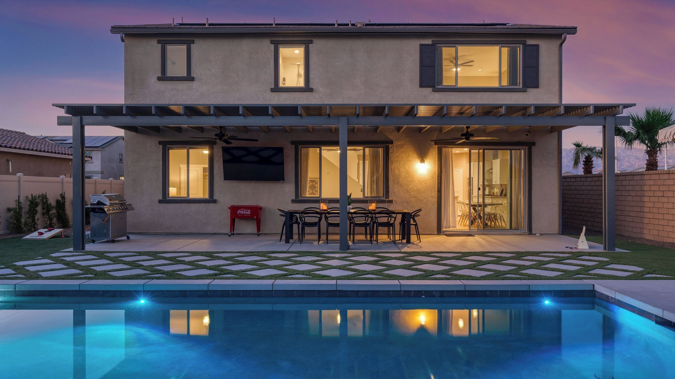 Une maison à deux étages dotée d’un patio couvert, d’une piscine et d’un coin repas.