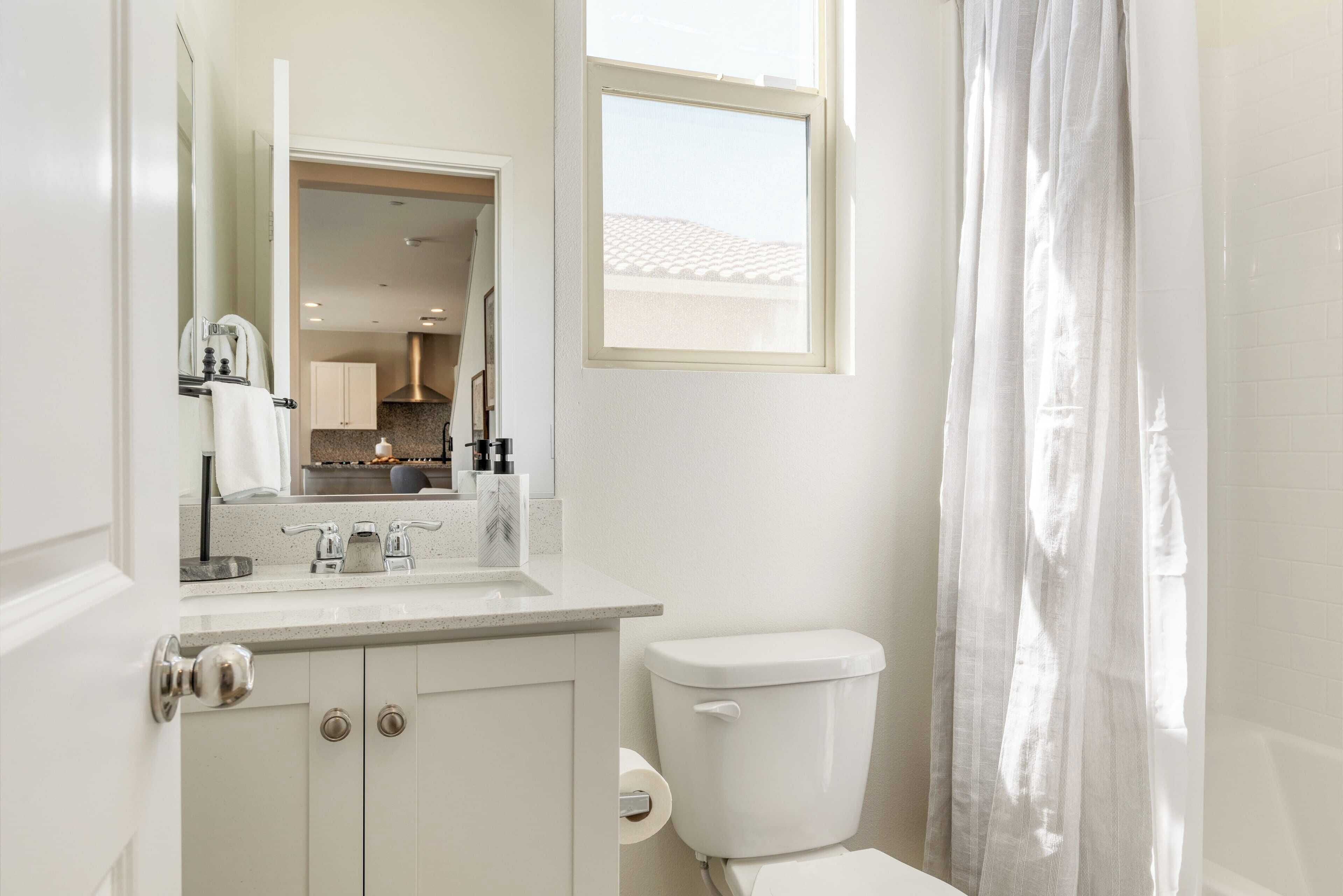 A bathroom with a toilet, sink, and mirror.