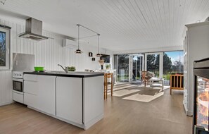 A modern kitchen with white cabinetry, a central island, and a dining area with a view of the outdoors. - Stunning home in Hemmet with kitchen (Hemmet)