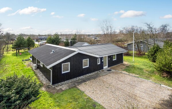 A modern two-story house with a dark exterior, a metal roof, and a gravel driveway. - Stunning home in Hemmet with kitchen (Hemmet)