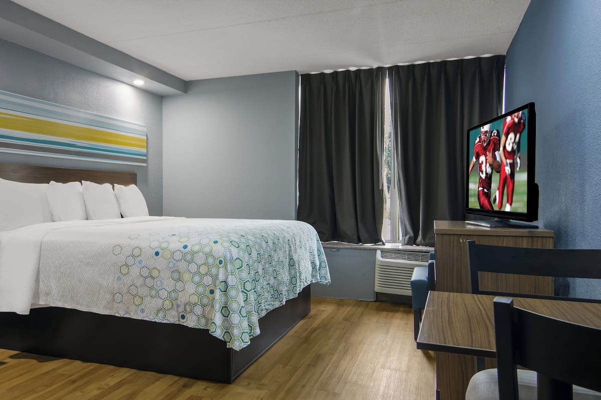 Une chambre d’hôtel avec un lit, une télévision, un bureau et une chaise.