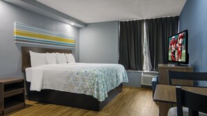 Une chambre d’hôtel avec un lit, une télévision, un bureau et une chaise.