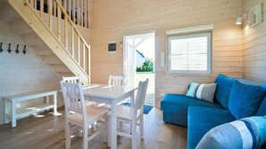 A wooden interior with a dining table, chairs, a blue sofa, and a staircase. - 1 bedroom amazing home in Mrzezyno (Mrzezyno)