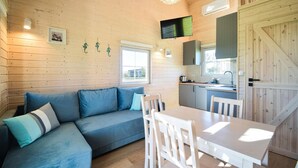 A cozy cabin interior with a sofa, dining table, and kitchen area. - 1 bedroom amazing home in Mrzezyno (Mrzezyno)