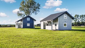 Two small, single-story houses with attached garages, set in a grassy field with a clear sky. - 1 bedroom amazing home in Mrzezyno (Mrzezyno)