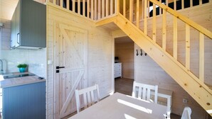 A wooden interior with a kitchen area, a dining table, and a staircase. - 1 bedroom amazing home in Mrzezyno (Mrzezyno)