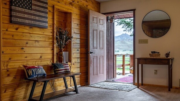 Un interno in legno con una panchina, una porta che dà all'esterno e uno specchio appeso al muro.