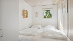 Un dormitorio con cama, ventana y una cesta tejida fijada a la pared.