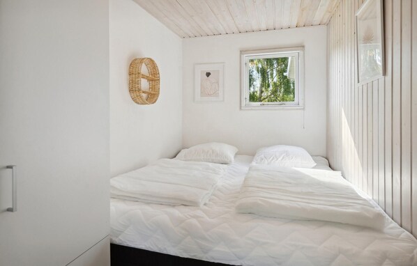 A bedroom with a bed, a window, and a wall-mounted woven basket.