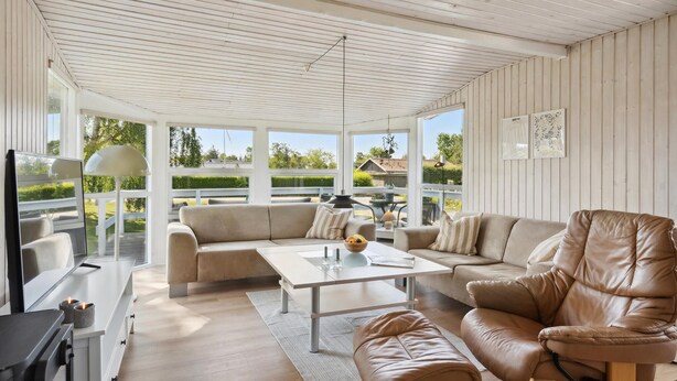 Una sala de estar moderna con sofá, sillón y mesa de centro. Hay una chimenea y vistas al exterior.
