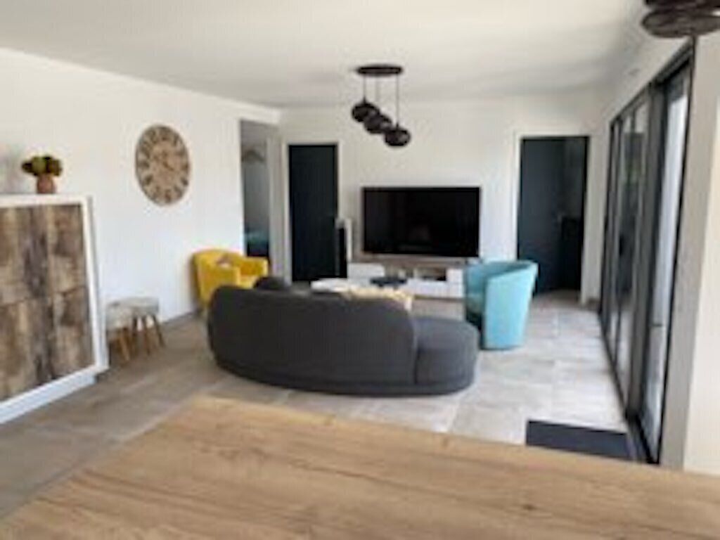 A modern living room with a sectional sofa, a flat-screen TV, and a minimalist design.