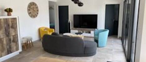 A modern living room with a sectional sofa, a flat-screen TV, and a minimalist design.
