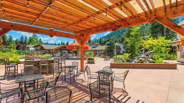 An outdoor patio with wooden pergola, tables, and chairs. - Icicle Village Blizzard Pool Parking (Leavenworth)
