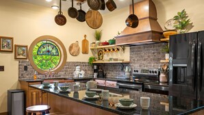 A kitchen with a central island, black appliances, and a brick backsplash. - Howards Hollow! Earth Home at The Forgotten Forest! (Kodak)