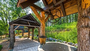 A rustic wooden structure with a stone bench and a fire pit. - Howards Hollow! Earth Home at The Forgotten Forest! (Kodak)
