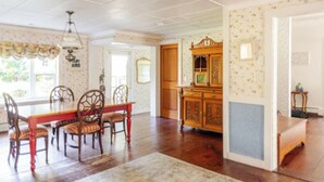 A dining room with a wooden table and chairs, a chandelier, and a wooden cabinet.