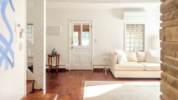 A living room with a white sofa, a small side table, and a door leading to another room.