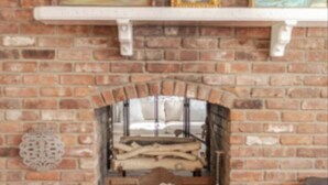 A brick fireplace with a mantel shelf displaying framed artwork.