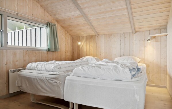A single bed with white bedding in a room with wooden walls and a sloped ceiling. - Stunning apartment in Rønde with sauna (Rønde)