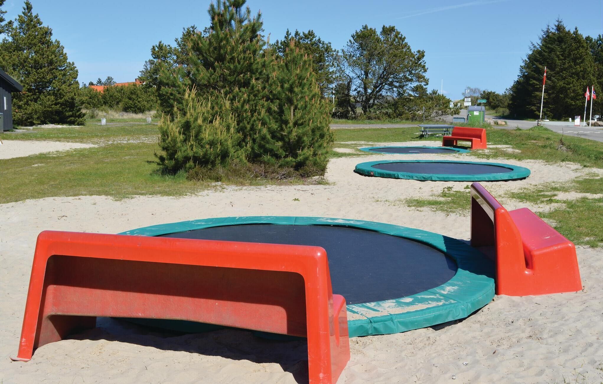 Une zone sablonne comprenant plusieurs trampolines et des dispositifs de sécurité.