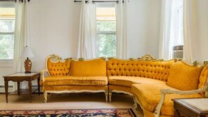A room with a large, ornate yellow sofa, a small wooden table, and a patterned rug. - Ski - Luxury Retreat Home - Stream, Waterfalls! (Palenville)