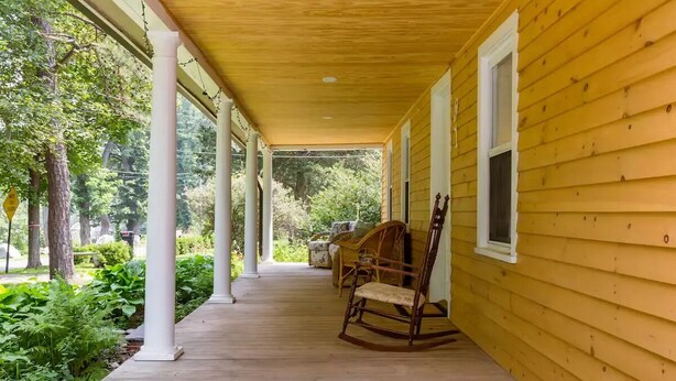 A covered porch with wooden columns and a rocking chair. - Ski - Luxury Retreat Home - Stream, Waterfalls! (Palenville)