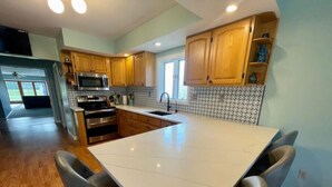 Una cucina moderna con mobili in legno, elettrodomestici in acciaio inossidabile e una grande isola con sgabelli da bar.