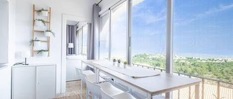 Eine moderne Küche mit großem Fenster, weißen Schränken und einer Holzleiter-Regal mit Pflanzen.