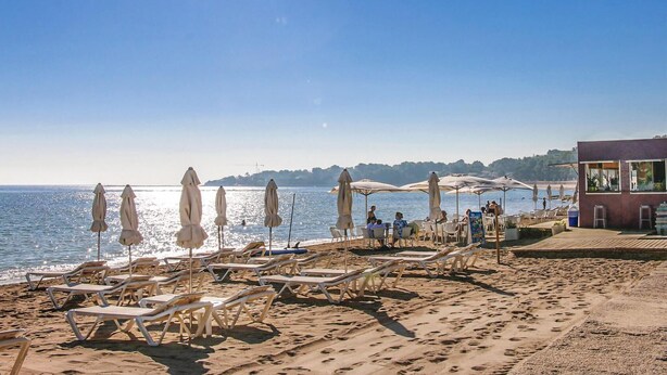 A beach with sun loungers and umbrellas, a building with artwork, and a clear view of the sea. - Lovely home in El Rafol D'Almunia (El Rafol D'Almunia)