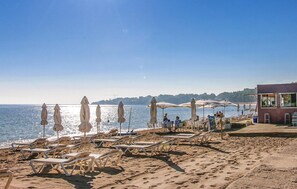 A beach with sun loungers and umbrellas, a building with artwork, and a clear view of the sea. - Lovely home in El Rafol D'Almunia (El Rafol D'Almunia)