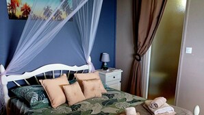 A bed with a canopy, pillows, a bedside table with a lamp, and a painting on the wall.