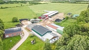 An aerial view of a farm with barns, a silo, and open fields.