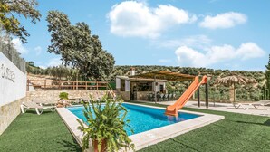 A pool area with a slide, outdoor seating, and a pergola.