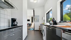 A modern kitchen with a coffee maker, a washing machine, and a window with a view of trees. - 3 bedroom awesome home in Vig (Vig)