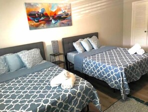 A hotel room with two beds, each with patterned bedding, a nightstand, a lamp, and a painting on the wall. - SOLYMAR II MIAMI BEACH HOUSE (Miami)