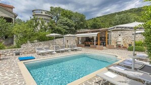 A pool area with lounge chairs, a stone wall, and a stone building in the background. - Beautiful home in Koromacno-Brovinje (Koromacno-Brovinje)