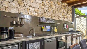 A kitchen with a stone wall, stainless steel appliances, and a built-in oven. - Beautiful home in Koromacno-Brovinje (Koromacno-Brovinje)